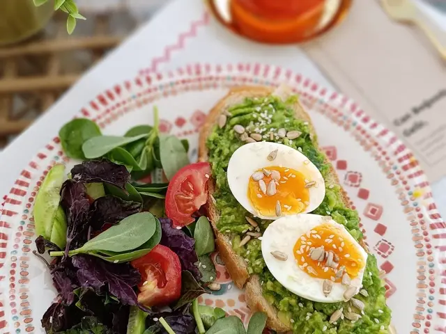 A plate of avocado toast with boiled egg and a green side salad